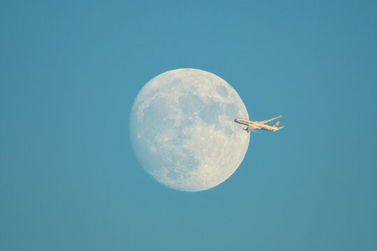 Japan Airlines Airbus A350-900 (JA01XJ) passing in front of the moon during climb after departure in the evening sky