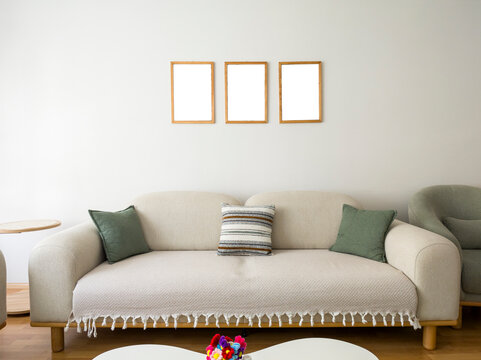 Bright Living Room Interior Featuring Beige Sofa and Three Blank Picture Frames Mockup
