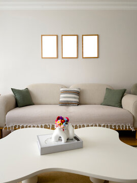 Living Room Interior Mockup with Three Empty Frames Hanging Above Sofa on Wall