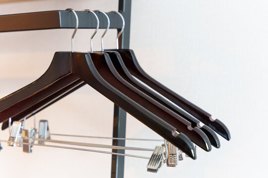 Black empty clothes hangers lined across modern metal clothing rail, close up wardrobe rack detail for closet organization, garment storage, retail display, minimalist interior, and polished hardware