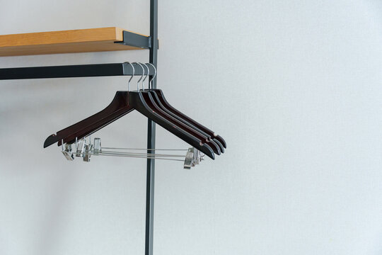 Modern wardrobe rail with empty black clothes hangers under wooden shelf, organized closet storage detail featuring metal rack, home interior furniture fixture, clean arrangement, and open hanging