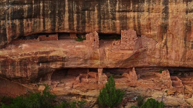 Golden sunset light illuminates the ceremonial stone masonry walls sheltered inside the natural alcove at Mesa Verde Fire Temple