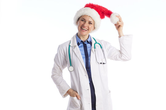 A professional physician in a white lab coat holds the tip of her Santa hat, bringing a joyful and festive mood to the healthcare environment during the holidays.