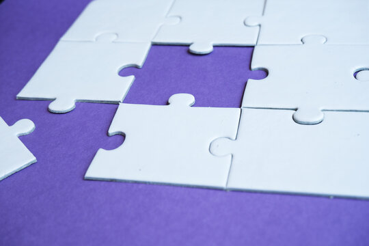 An incomplete puzzle with separate pieces. A puzzle arrangement against a purple background. Concept of finding solutions and problem-solving.
