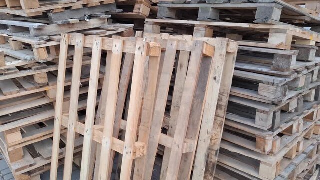 Stacked wooden pallets in close view at a storage area. Industrial material, warehouse supply, transport logistics, rough timber, cargo equipment.