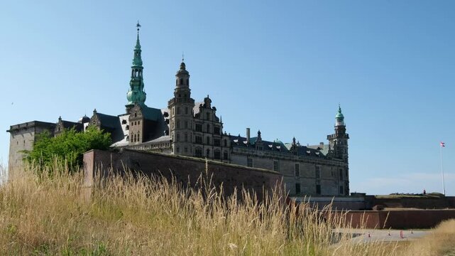 Majestic Kronborg Castle reveal on a sunny day, framed by dry grasses. Travel to Denmark, see landmark, and explore history