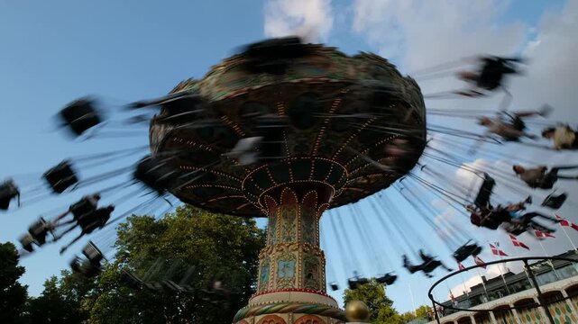 A wave swinger ride whirls in Copenhagen's Tivoli Gardens. Blurry motion conveys speed, excitement. Use: travel, fun, recreation, amusement
