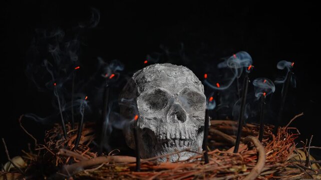 Black candles smoke surround and covers human skull in slow motion. Reading candle smoke ancient divination technique. Rising smoke from candles flames on the wick. Spiritual realm and fortune telling