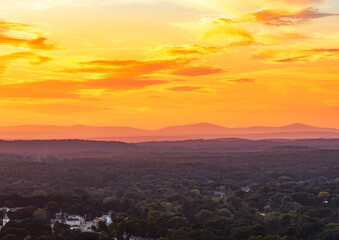 Fototapeta premium sunset landscape of woodland valley and small residential town
