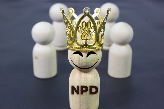 Conceptual peg doll representing a powerful person wearing a crown with NPD text and an evil smile, symbolizing narcissism, manipulation, toxic leadership, ego, authority, and psychological behavior.