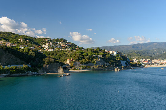 Hermoso paisaje costero mediterr&aacute;neo con aguas azules, colinas verdes salpicadas de casas y monta&ntilde;as en el horizonte en un d&iacute;a soleado
