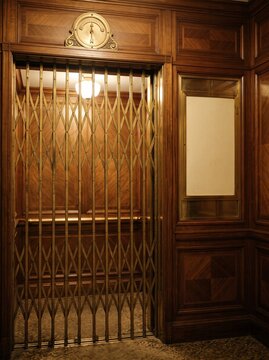 Closed antique elevator gate with empty framed notice board