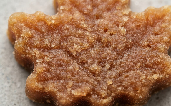Macro close-up of traditional Canadian maple sugar candy shaped like a maple leaf with crystalline texture for gourmet food and dessert concepts
