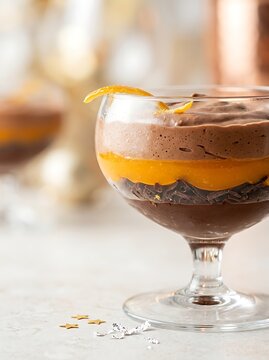 Chocolate orange mousse dessert layered in a elegant glass dish with festive garnish background
