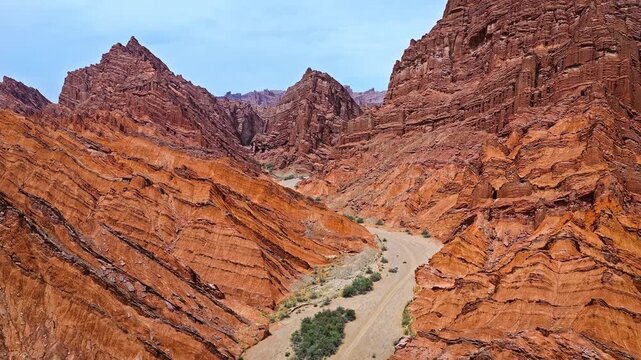 Aerial view of dirt road through steep red sandstone cliffs in Kuqa Grand Canyon, Xinjiang, China