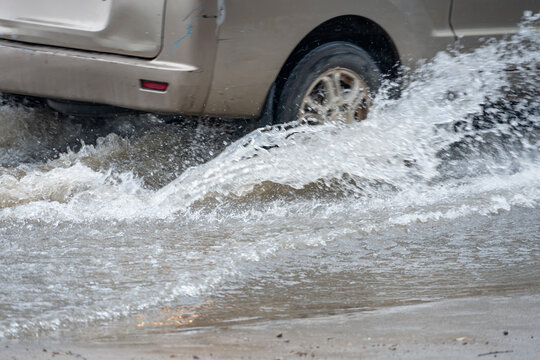 Car driving through puddle creating big water splash on wet rainy road