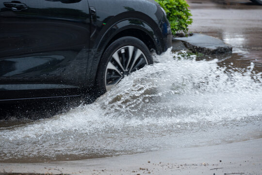 Car driving through puddle creating big water splash on wet rainy road