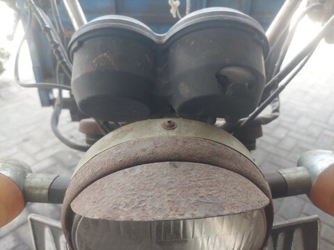 Close up of an old rusted three wheeler or tosa tricycle headlight, showing corrosion texture details and a worn classic impression.