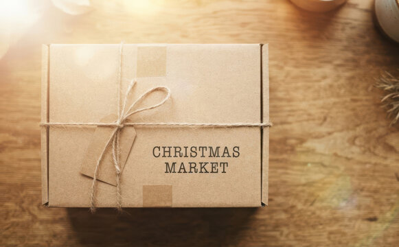 Wrapped cardboard gift box with Christmas Market text and string tie on a rustic wooden table for holiday shopping concepts