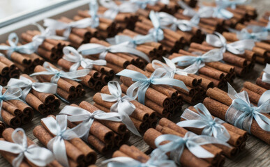 Obraz premium Bundles of cinnamon sticks tied with light blue ribbons arranged neatly for rustic wedding favors, holiday crafts, and artisanal home decor projects
