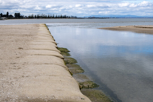 A geotextile sandbag groyne extending into sea at the Laverton Creek estuary mouth in Altona. Coastal erosion control infrastructure in Melbourne, Victoria, Australia