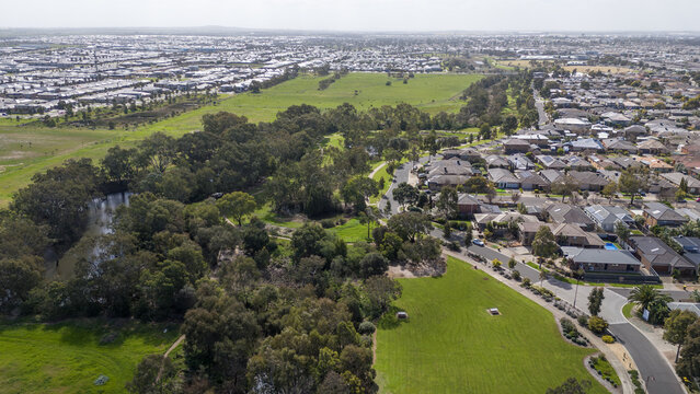 Aerial view of residential housing estates bordered by dense green tree canopy along the Werribee River corridor in Tarneit, outer Melbourne, Victoria, Australia