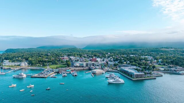 Bar Harbor, Maine aerial hyperlapse over Frenchman Bay looking toward downtown, harbor piers, and low clouds rolling over the mountains of Mount Desert Island.