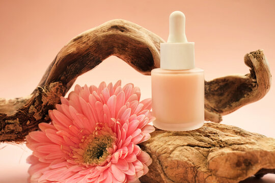 Cosmetic serum bottle on delicate flowers background, natural  scincare cosmetics, beauty and facial care concept image, selective focus, shallow DOF