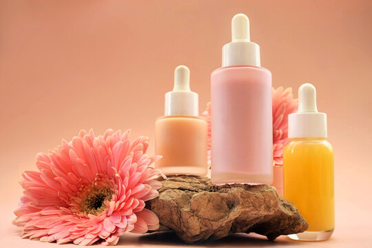 Cosmetic serum bottles on delicate flowers background, natural scincare cosmetics, beauty and facial care concept image, selective focus, shallow DOF