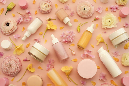 Cosmetic serum bottles on delicate flowers background, natural scincare cosmetics, beauty and facial care concept image, selective focus, shallow DOF