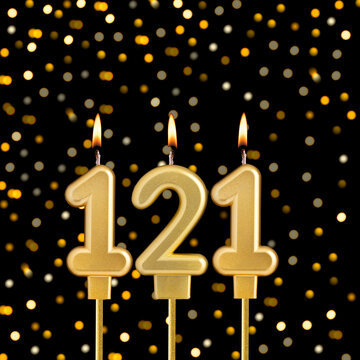 Number 121 birthday candle on a black background with blurred lights