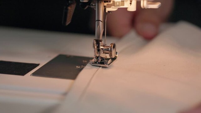 Close up of sewing machine presser foot stitching linen fabric at home