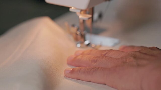 Hands guiding linen fabric while sewing at home