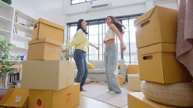 Two young Asian woman dances in living room. Asian women with a smile relaxing at home, happy and in good mental and physical health
