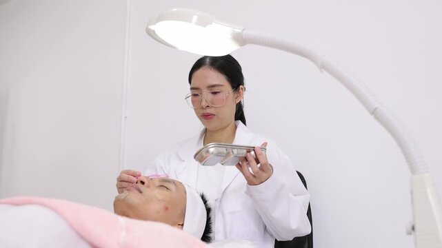 Esthetician applying facial gel mask skincare treatment to a man. Professional female beautician in a white coat applying a cosmetic gel to a male client's face with a spatula in a beauty clinic.