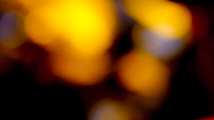 Fototapeta premium Abstract warm golden bokeh light effect with glowing circles on black background for seasonal celebration and decorative design