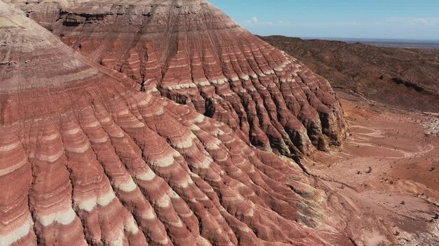Aerial view of dramatic red and white striped sandstone formations with layered erosion patterns in an arid desert landscape in Aktau Mountains, Altyn Emel National Park, Kazakhstan