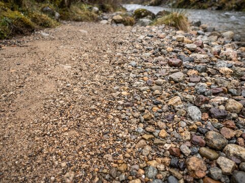 Gravel path beside river with pebbles and sand texture for outdoor background.