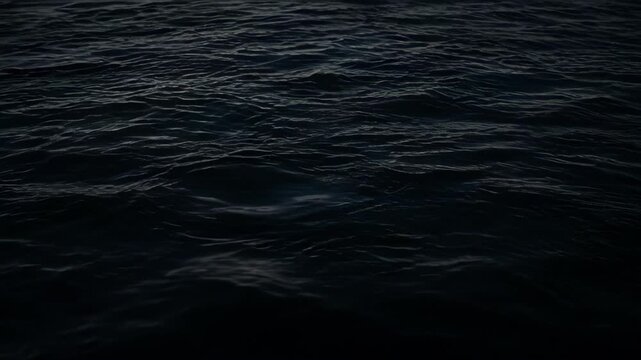 Dark sea surface with gentle wave ripple pattern creating moody ocean water texture background for atmospheric nature, marine design, coastal concepts, and abstract visual imagery