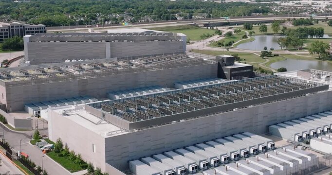 Aerial view of a large data center facility with extensive rooftop HVAC units and parking areas 