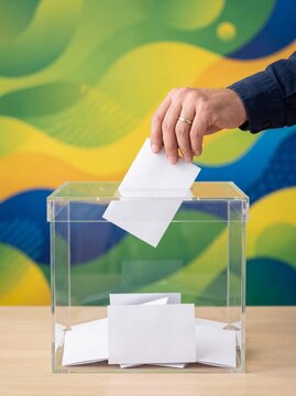 Casting a Vote: A person's hand inserts a ballot into a transparent ballot box, signifying a democratic process.