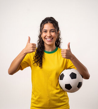 Brazilian Fanatic: A young, smiling woman in a yellow and green soccer jersey holds a ball, giving a thumbs-up, embodying the spirit of a devoted fan and supporter.
