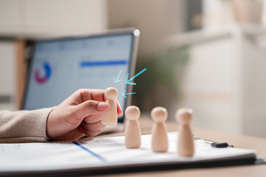 Human resources recruitment focus and talent acquisition headhunting. Woman hand picking chosen wooden figure candidate with arrow symbol.
