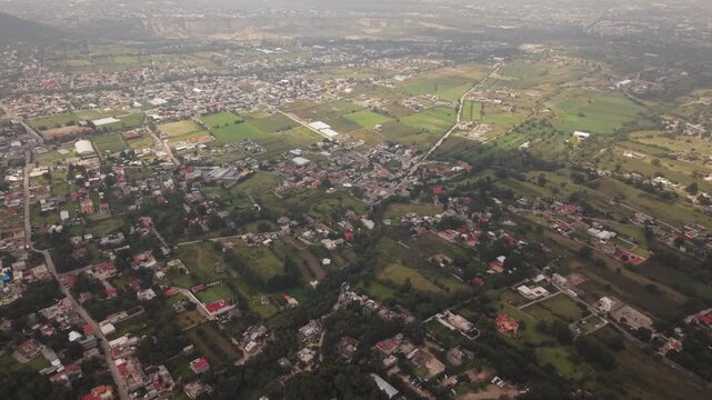 Peaceful aerial drone view of a rural village in Texcoco, Mexico, with sunlight and cloud shadows moving across the landscape