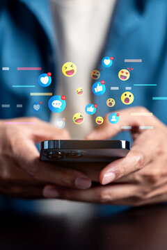 Social media network communication and online engagement reaction. Man hand holding smartphone using emoji emoticon heart like and message.