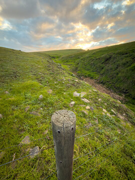 Rustic timber farm fence post with lush green fields behind on the Fleurieu Peninsula, South Australia