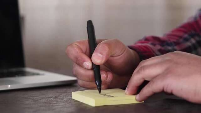 A man's hands writing the word &ldquo;Accountability&rdquo; on a sticky note