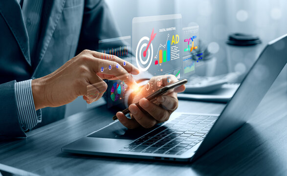 Digital marketing analytics concept with business professional using smartphone beside laptop showing virtual advertising dashboard, target campaign data and online ad performance