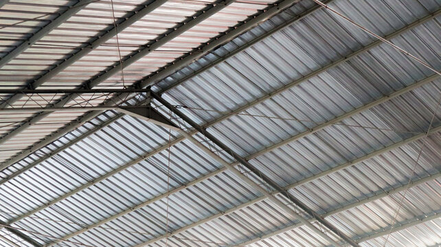 Low angle view of corrugated metal warehouse roof and steel trusses