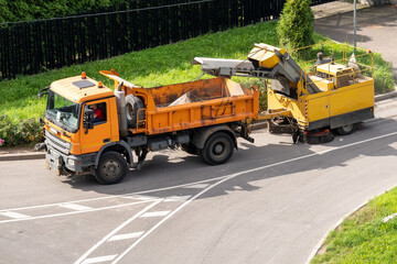 Municipal city street cleaning equipment on roads, dump truck with mechanical sweeper machine cleans road, industrial sweeping vehicle sweeps various small debris, sand, stones from roadway and curbs. © DimaBerlin
